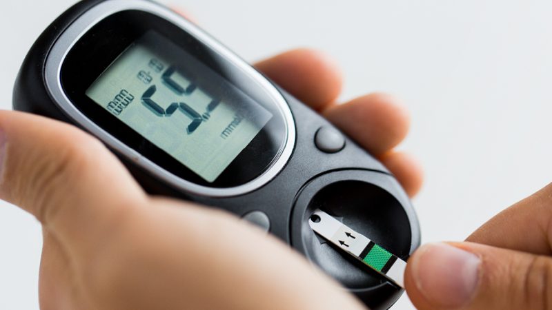 A persons hands holding a diabetes testing at home machine