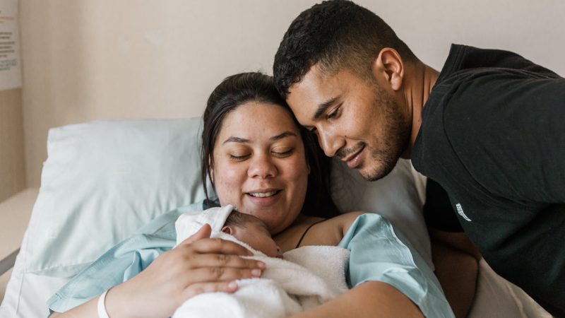 Mixed race couple with newborn baby in hospital bed