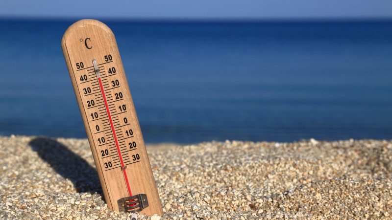 Thermometer on a beach shows high temperatures.