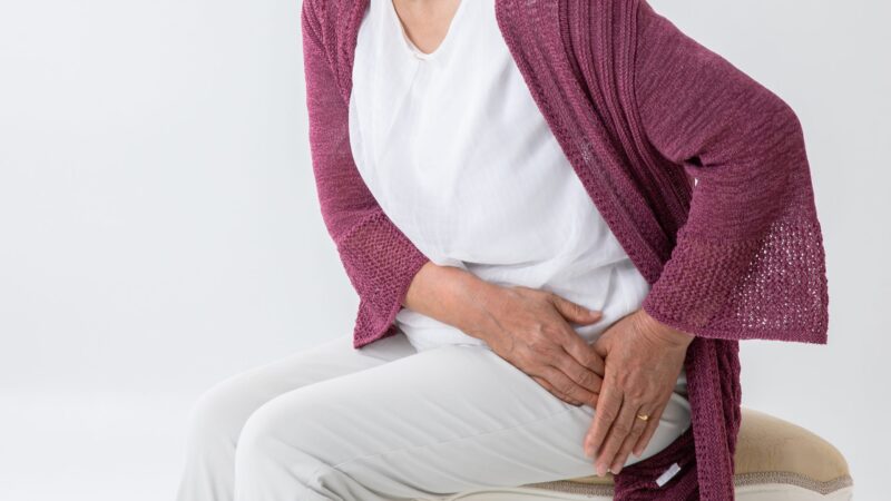 Lady sitting on a stool holding her hip
