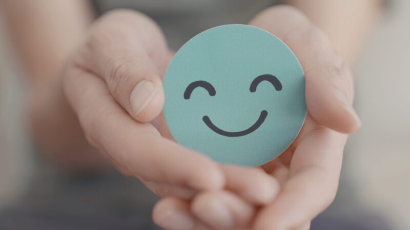 Hands holding green happy smile face