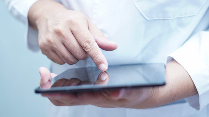 Asian smart man doctor holding digital tablet technology to search knowledge solve treatment for patient in nursing hospital ward : healthy strong medical concept.