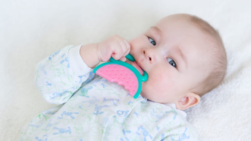 painful teething in infants, baby close-up with a toy