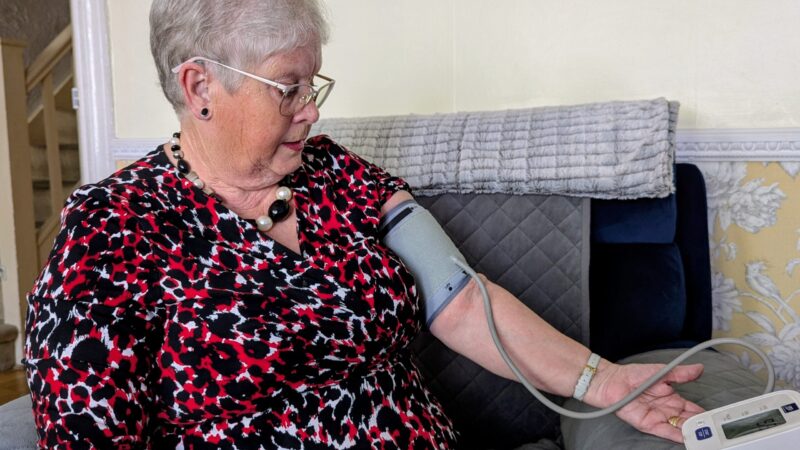 Joan taking a blood pressure reading using her home monitor