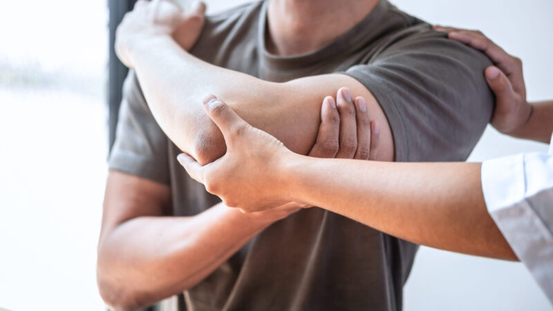Female Physiotherapist working examining treating injured arm of athlete male patient, stretching and exercise, Doing the Rehabilitation therapy pain in clinic.