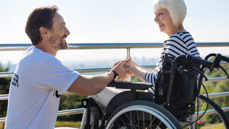 Ask me anything. Remarkable clever attentive guy holding senior woman by the hands while talking to her and making sure she feeling better