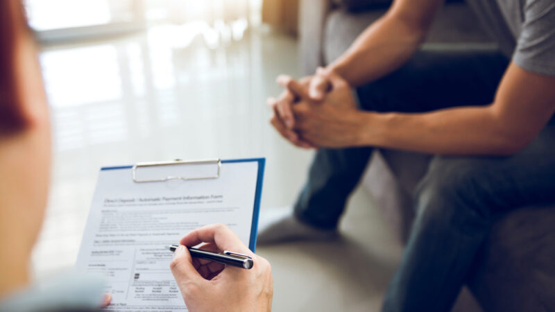 Asian doctor is examining the abnormal items of the body and diagnosing the disease in the paper with the medical report of the patient.