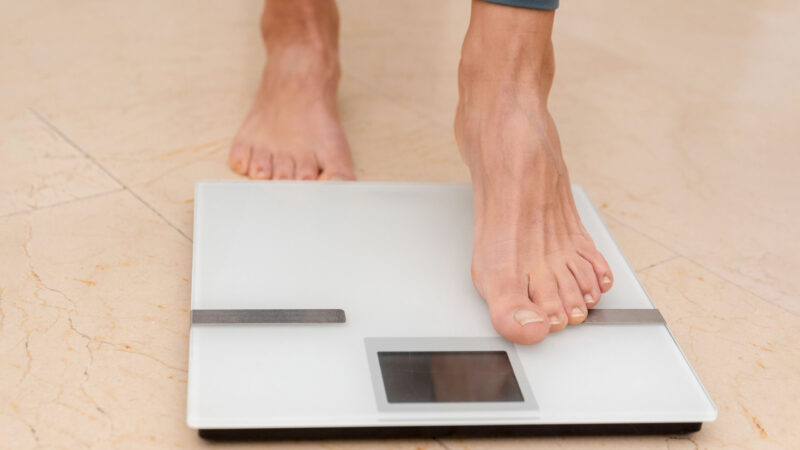 Close up of feet Stepping onto a Digital Scale to check weight, Healthy Lifestyle and Weight control