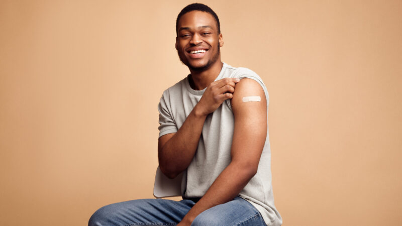Covid-19,Vaccinated,African,Man,Showing,Arm,With,Plaster,,Beige,Background